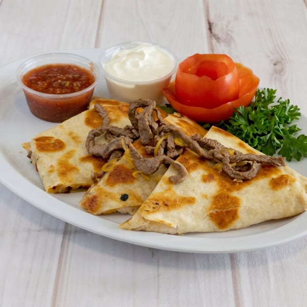 Steak quesadillas with salsa, sour cream, a tomato rose, and parsley on a white plate.